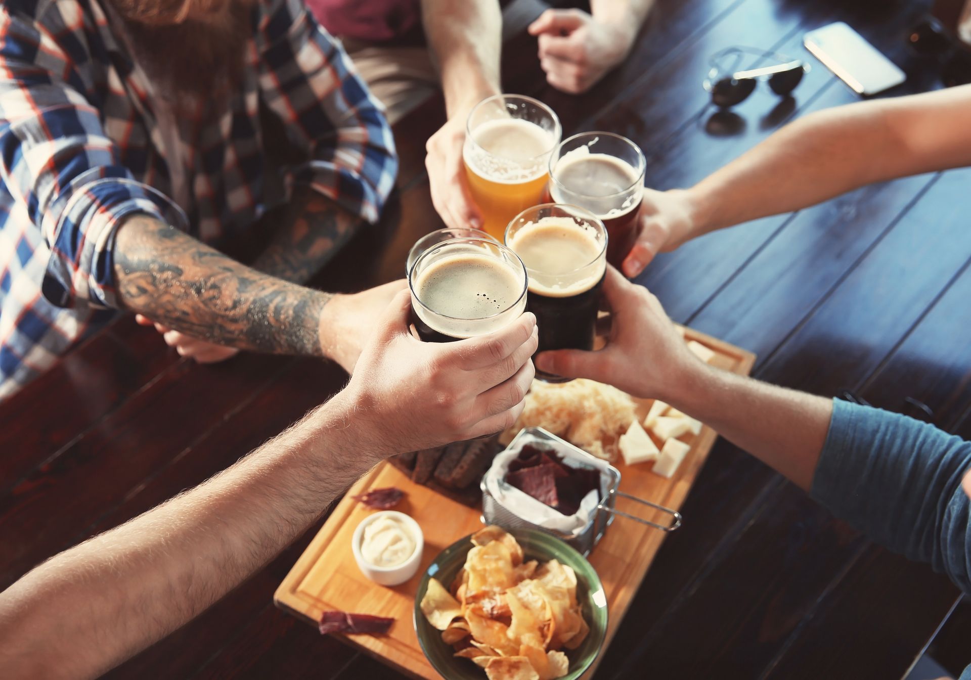 A group of people are toasting with beer and food at a table.