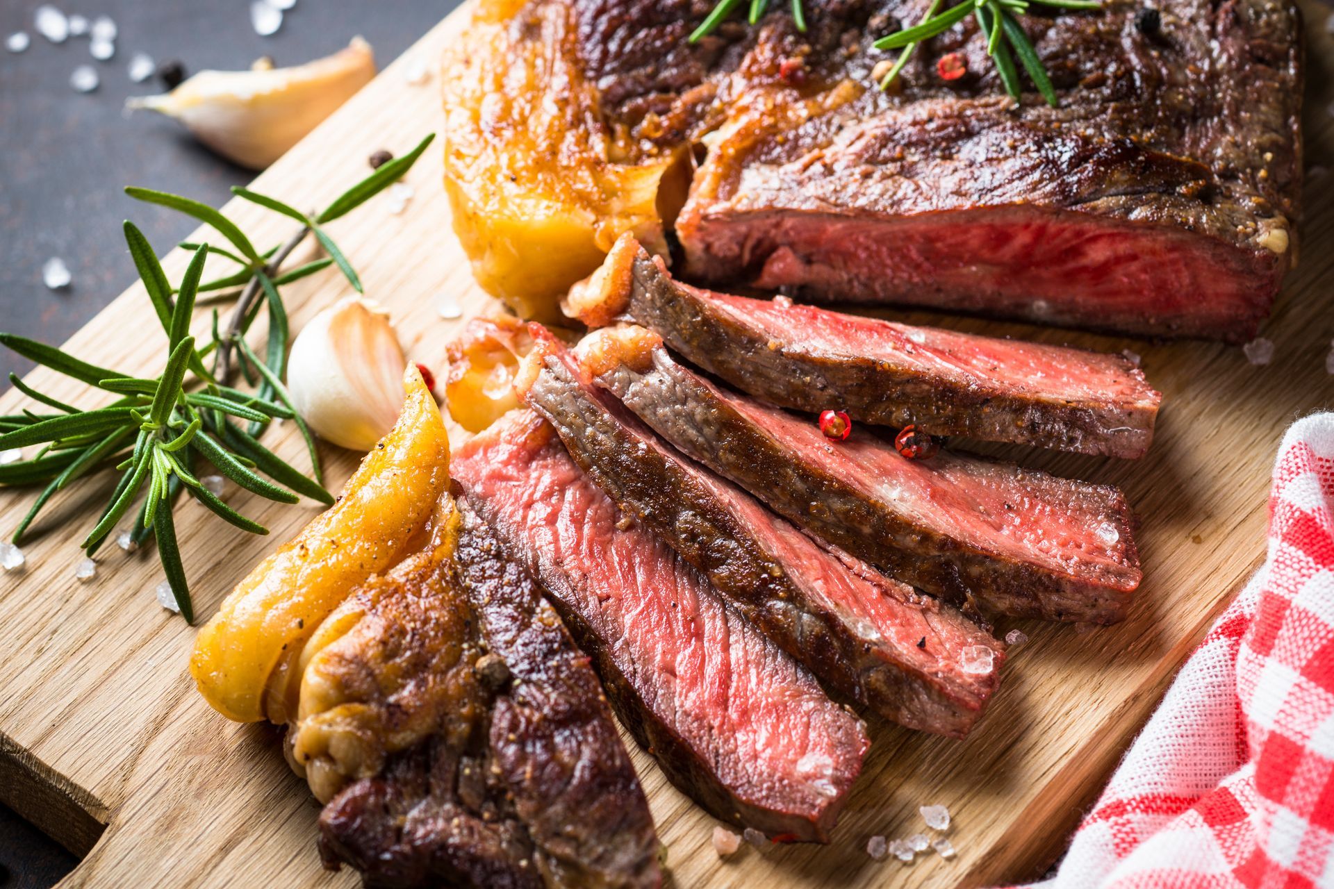 A large piece of steak is sitting on a wooden cutting board.