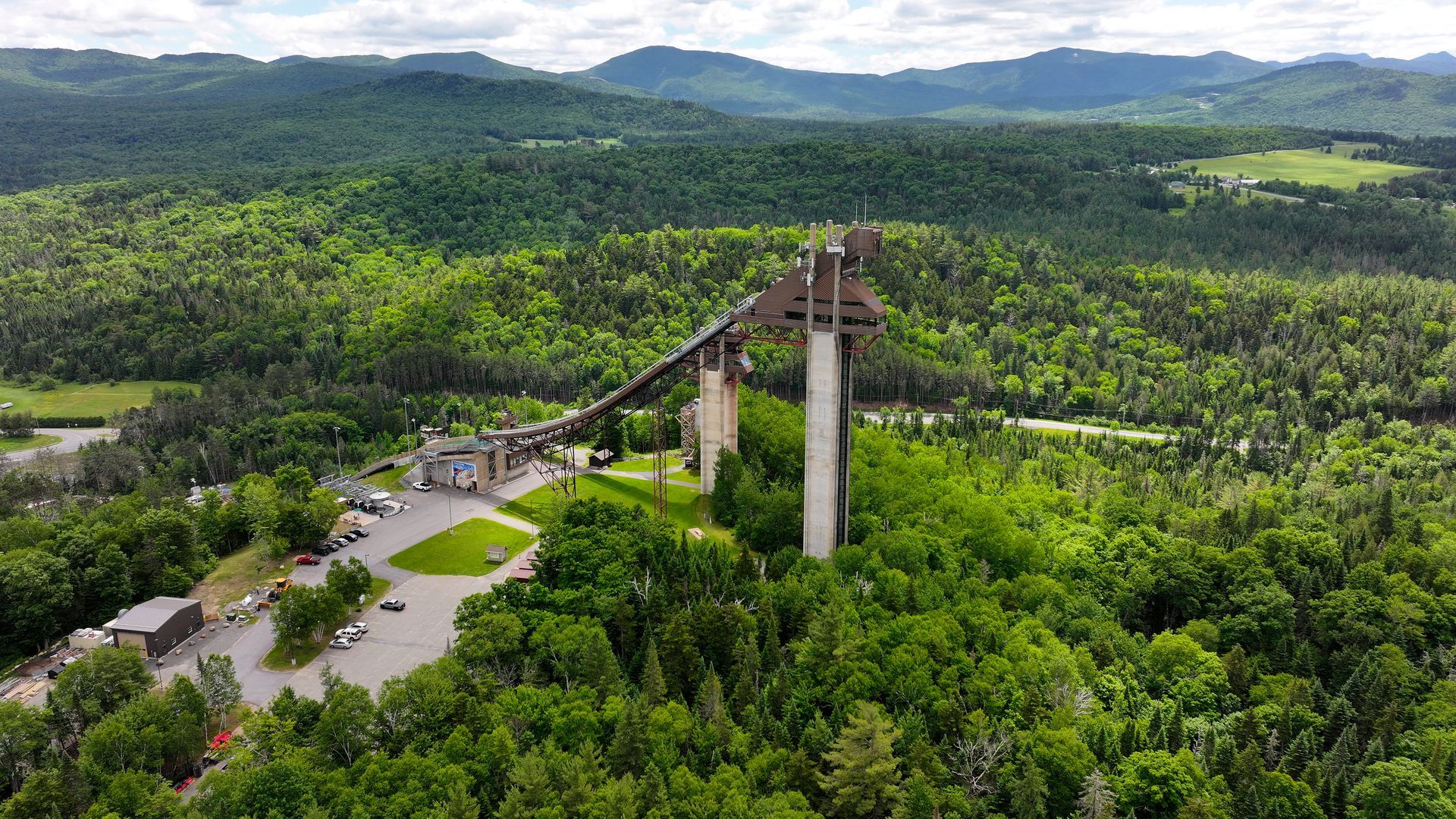 An aerial view of a large building surrounded by trees and mountains.