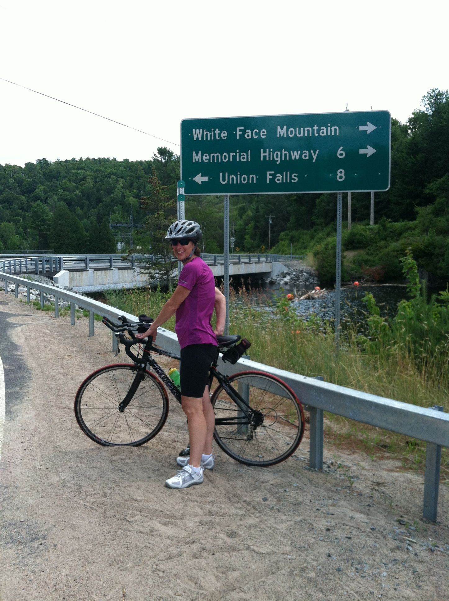 Two people are riding bikes down a dirt road in the woods.