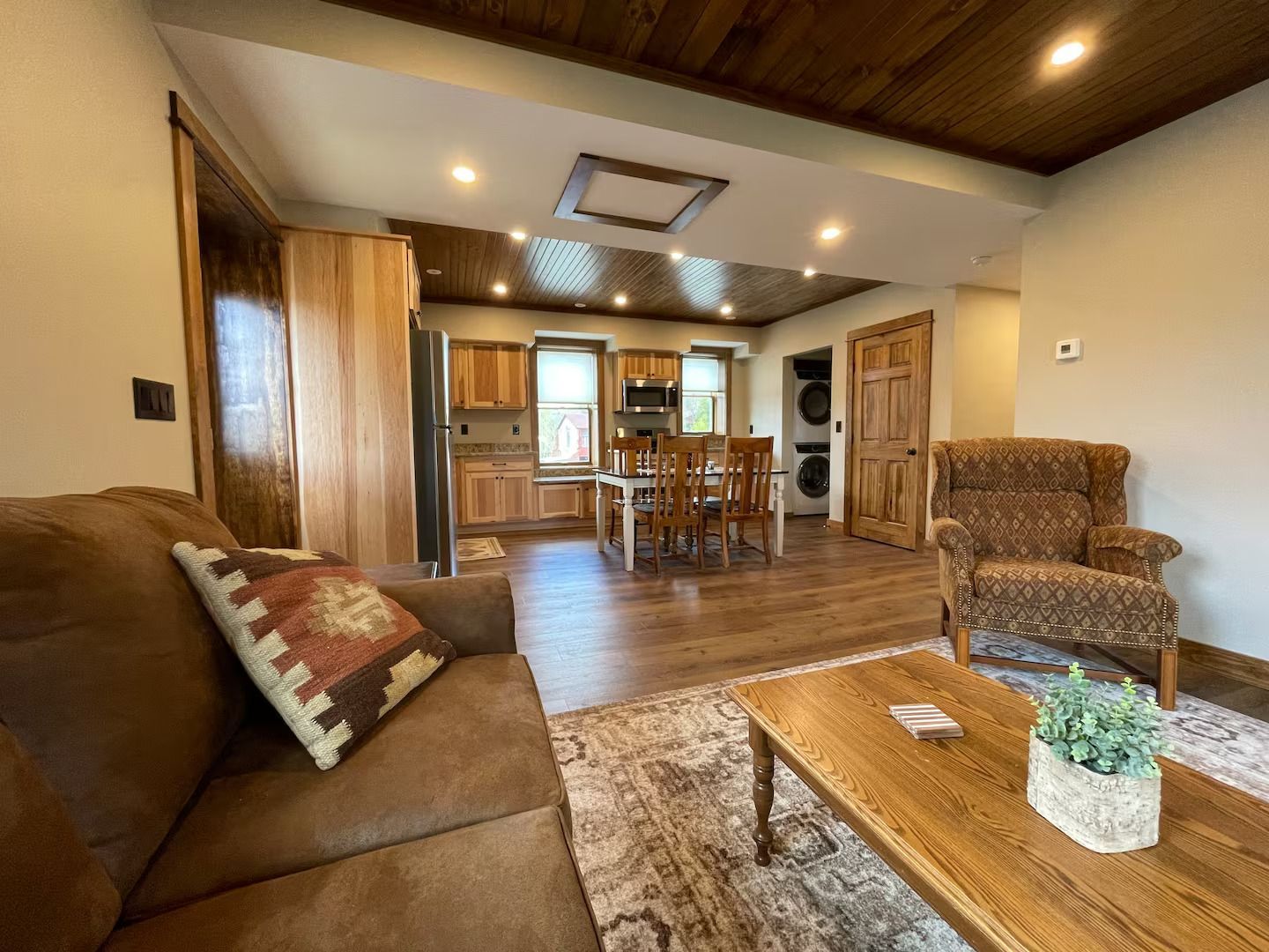 A living room with a couch , chair , coffee table and kitchen in the background.