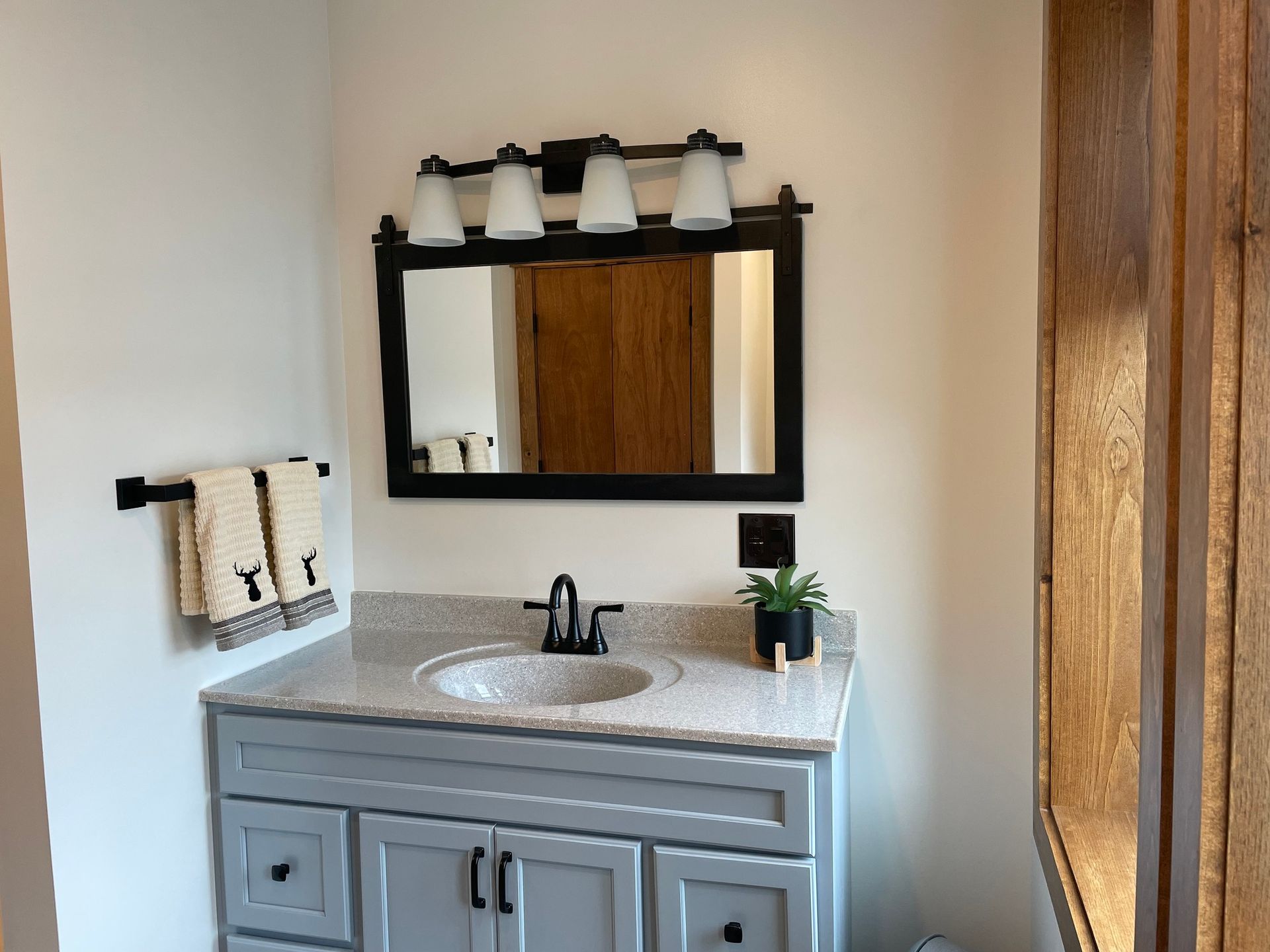 A bathroom with a sink , mirror and towel rack.