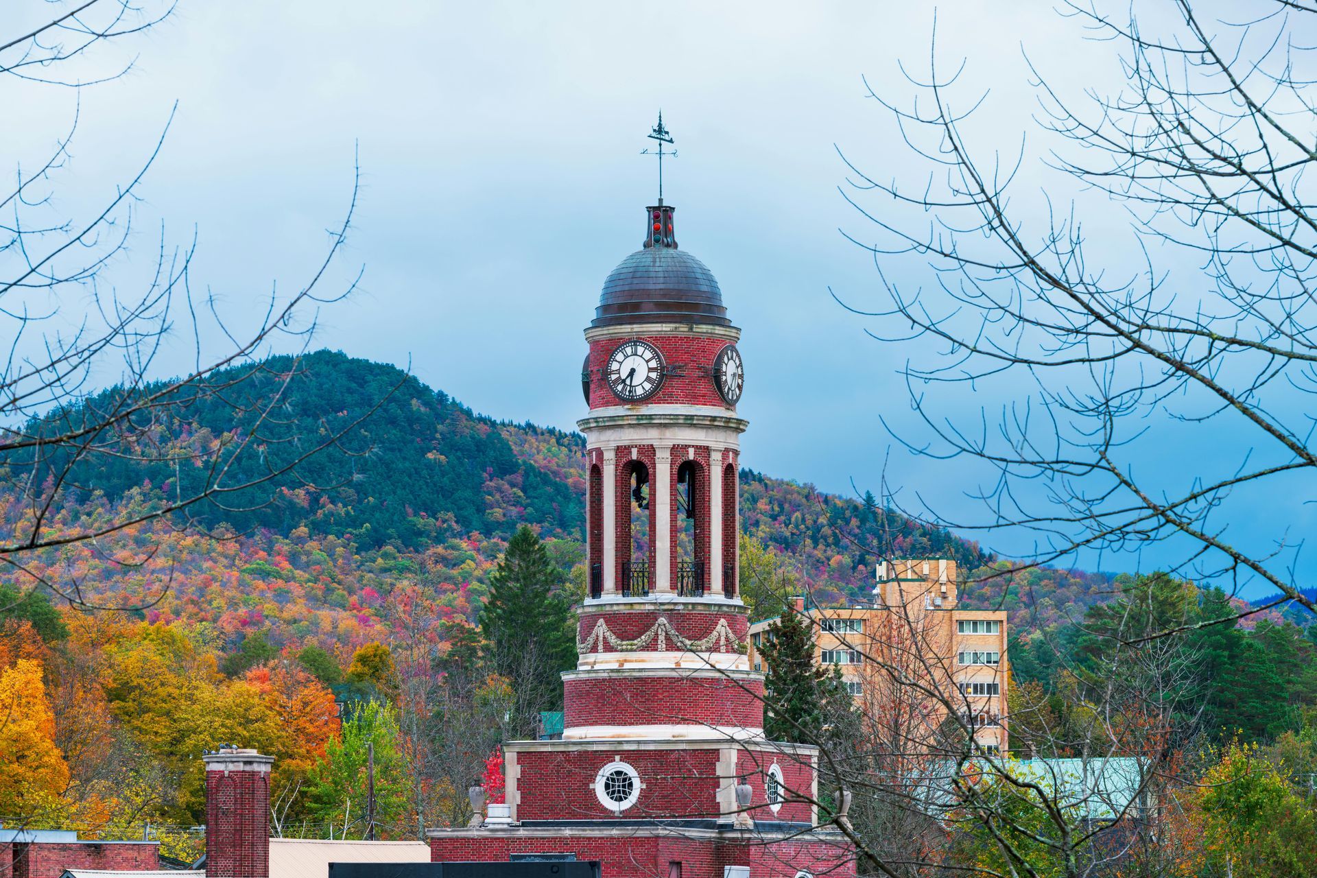 A clock tower with mountains in the background and trees in the foreground.