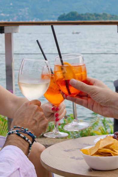Donna che si rilassa su una sedia a sdraio con un drink e una borsa rossa, con vista sull'acqua.