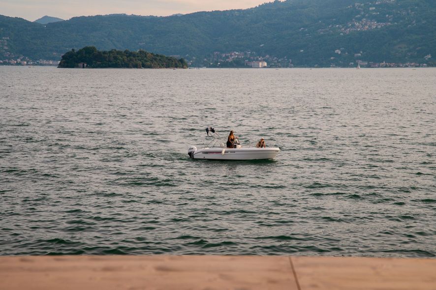 Una piccola barca bianca con due persone su un lago, con le montagne sullo sfondo.