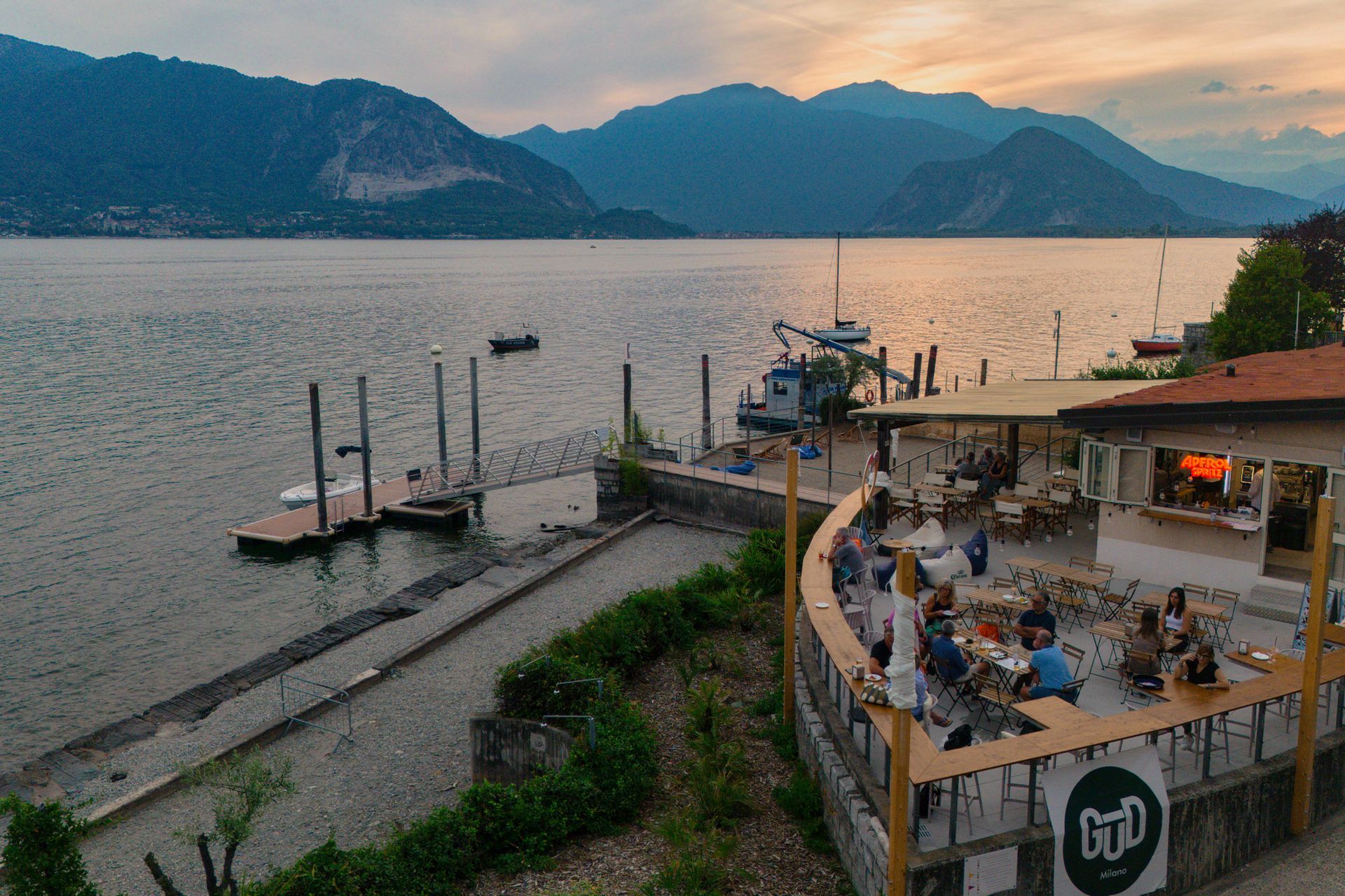 Una piccola barca su un molo su un lago; persone a bordo. Cartello GTD in primo piano.