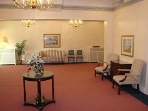 A formal lounge with peach-colored walls and carpet, featuring a central round table, a striped sofa, and upholstered chairs.