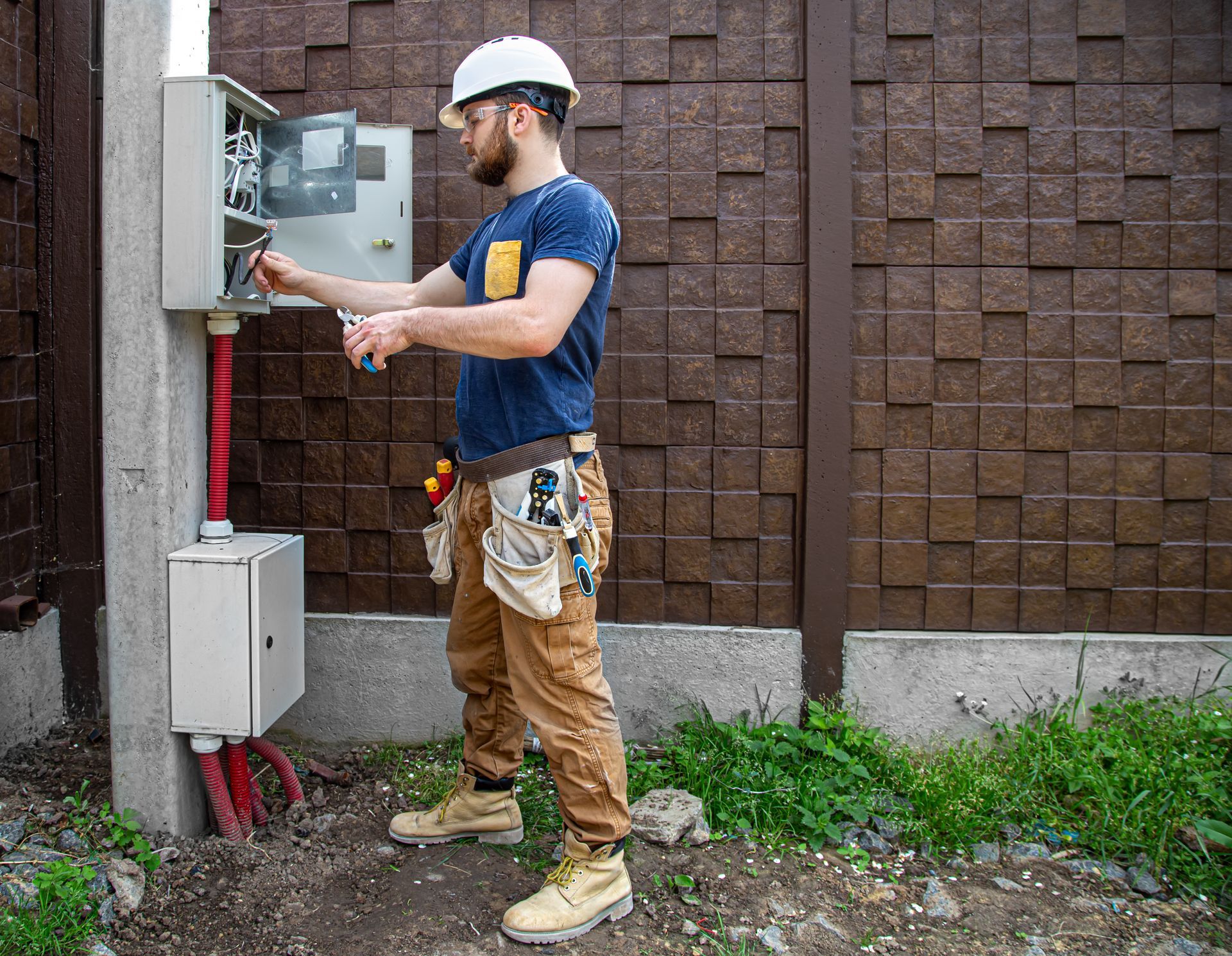 a man is working on an electrical box outside of a building .