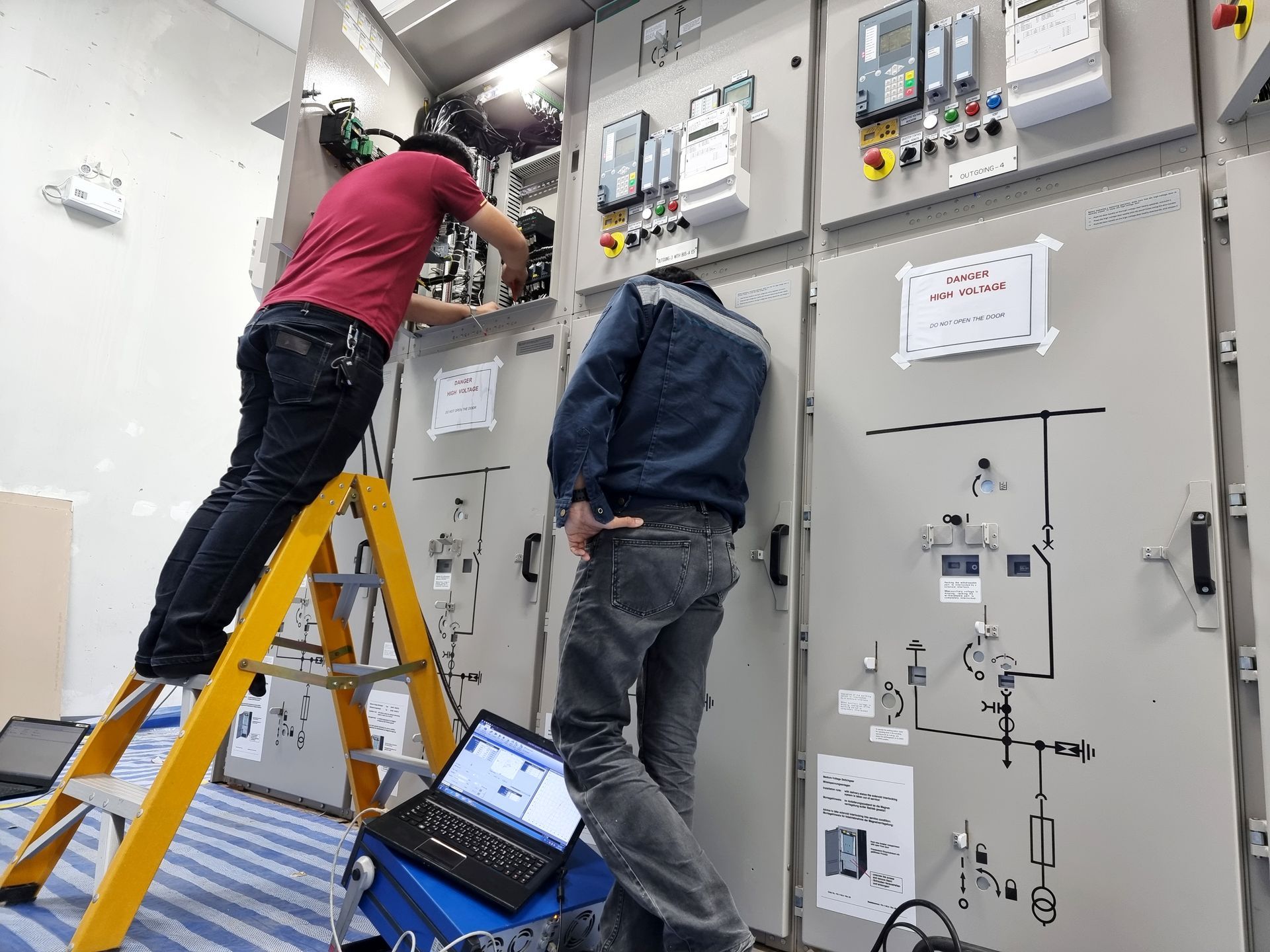 two men are working on a electrical panel in a room .