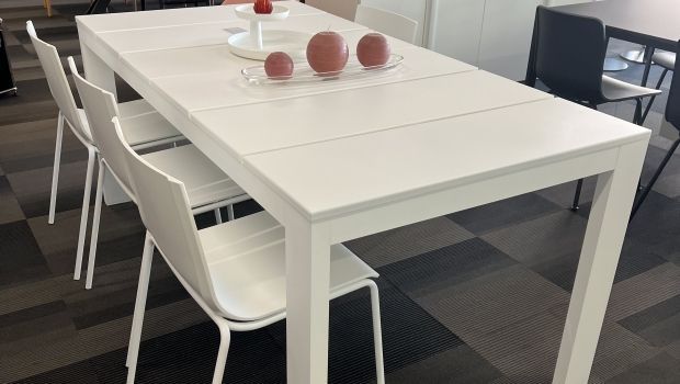 Una mesa blanca con sillas y pelotas encima