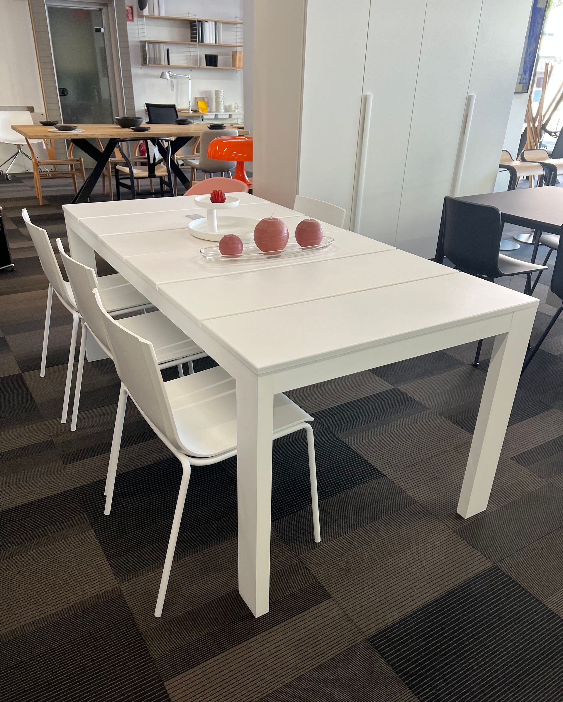 En una habitación hay una mesa y sillas blancas.