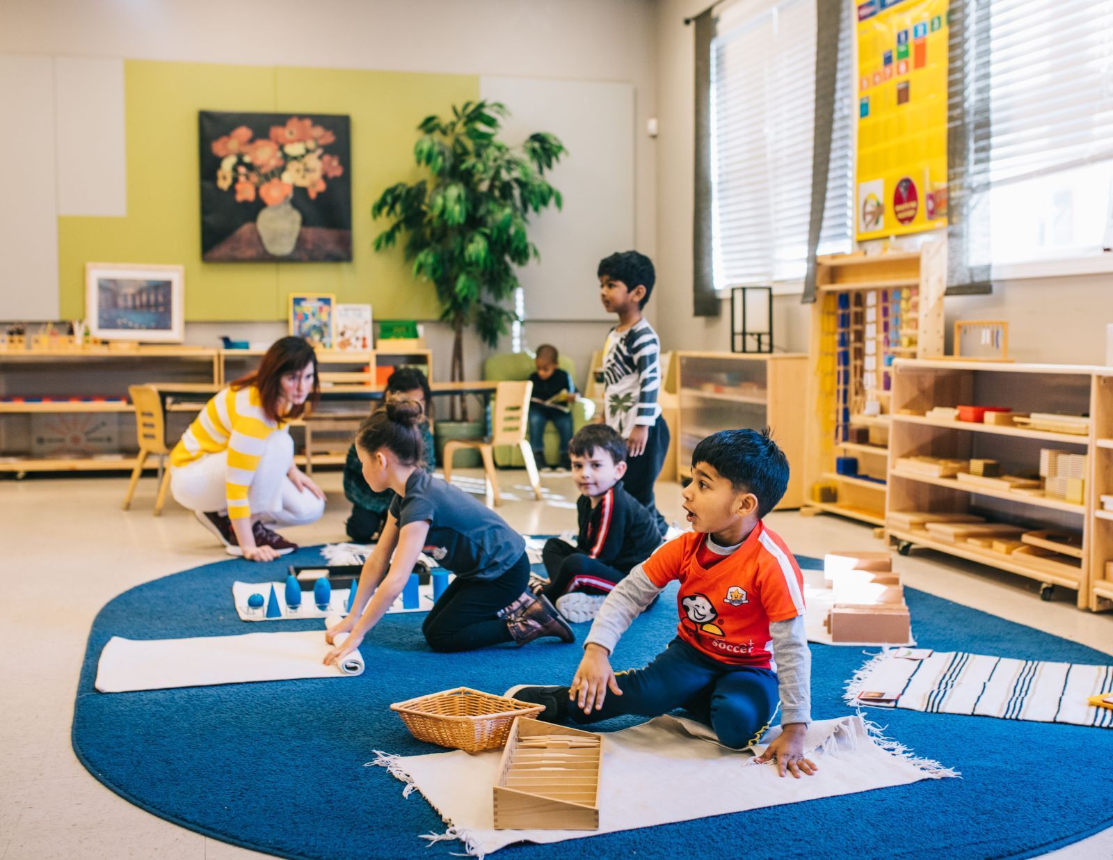 A group of children are sitting on the floor in a classroom.
