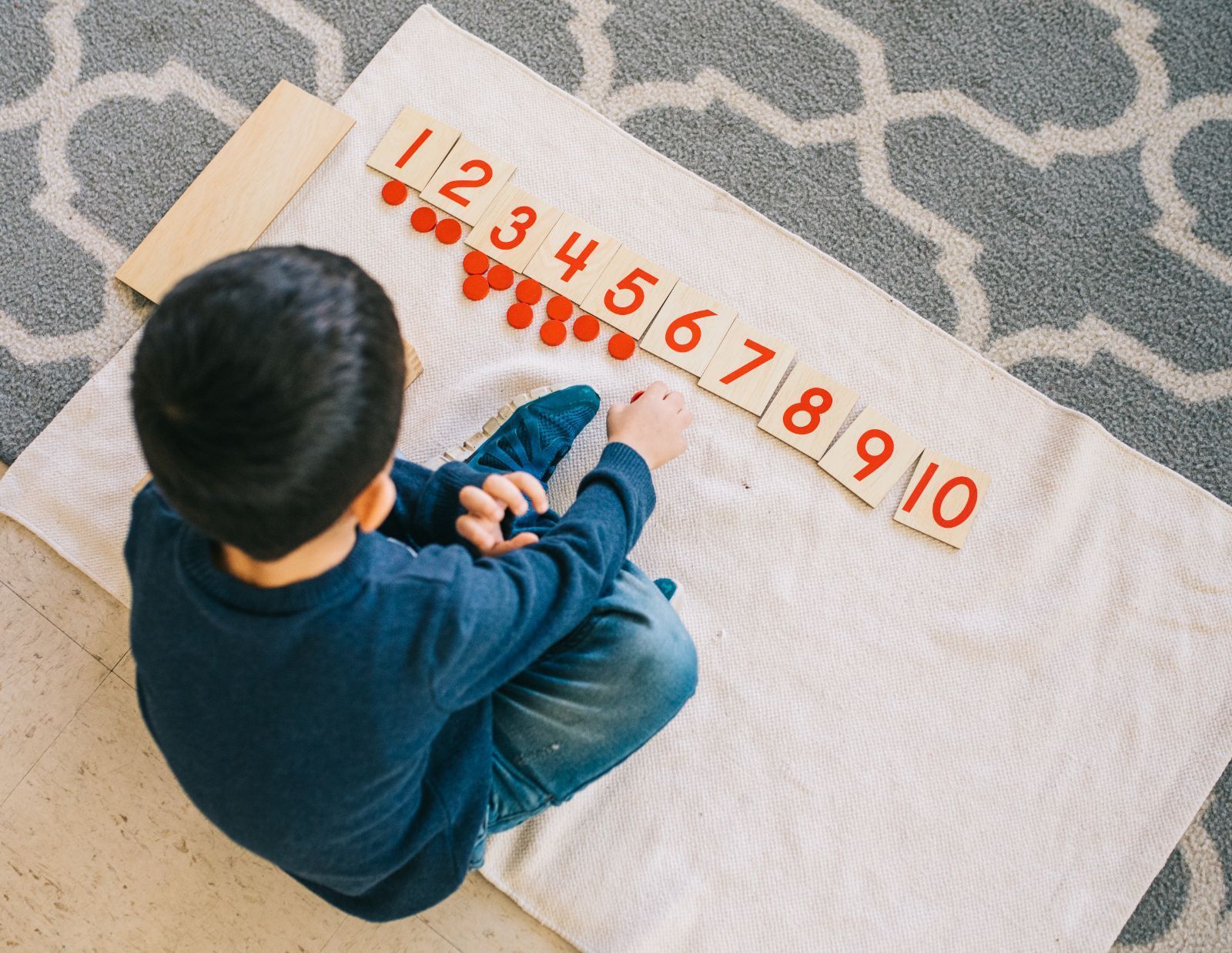 A young boy is sitting on the floor playing with numbers.