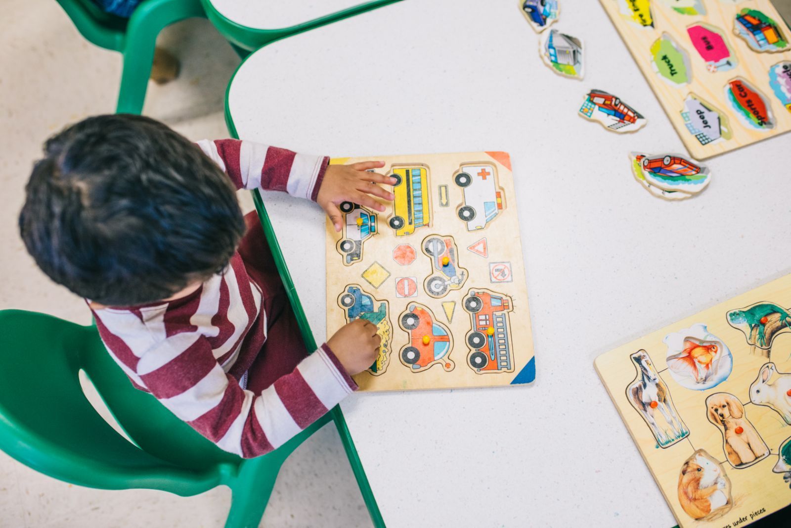 A young boy is sitting at a table playing with a puzzle.