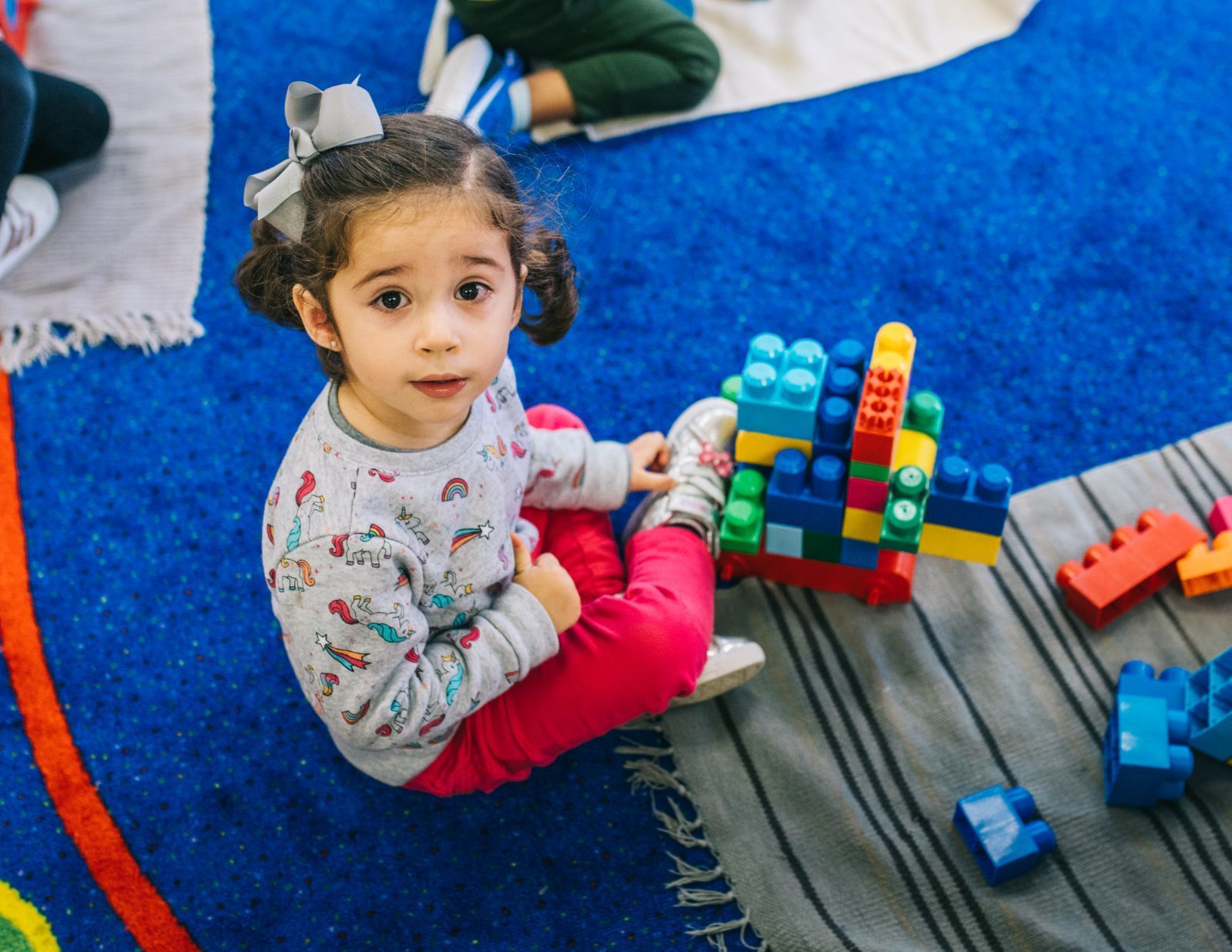 A little girl is sitting on the floor playing with blocks.