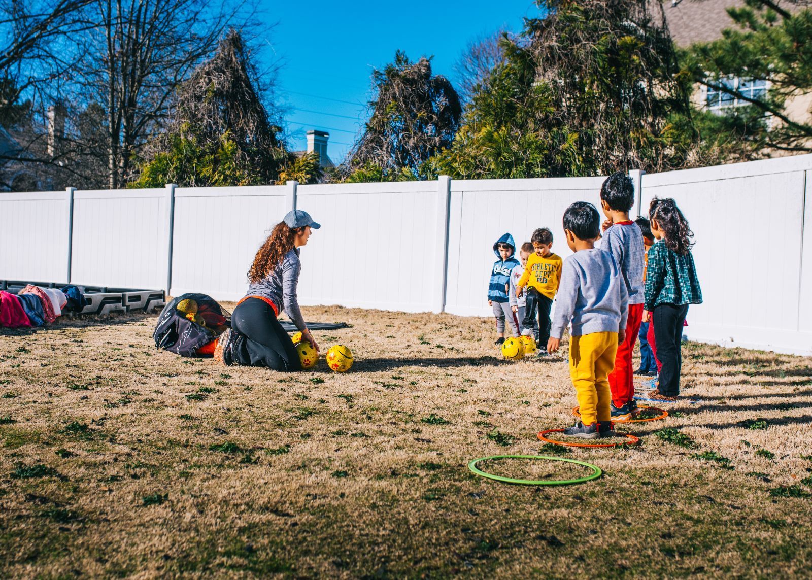 A group of children are playing with soccer balls in a yard.