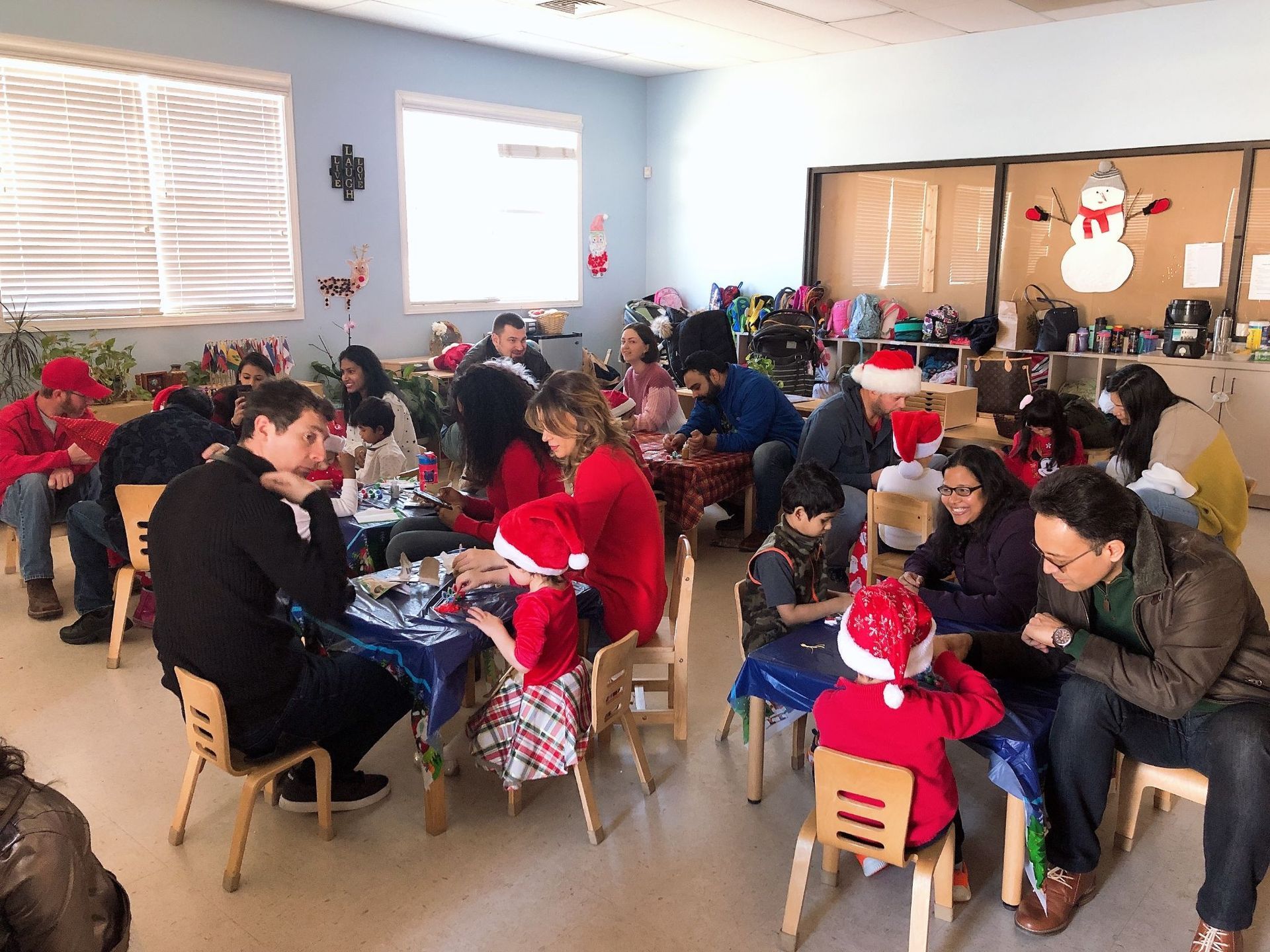 A group of people are sitting at tables in a room decorated for christmas.