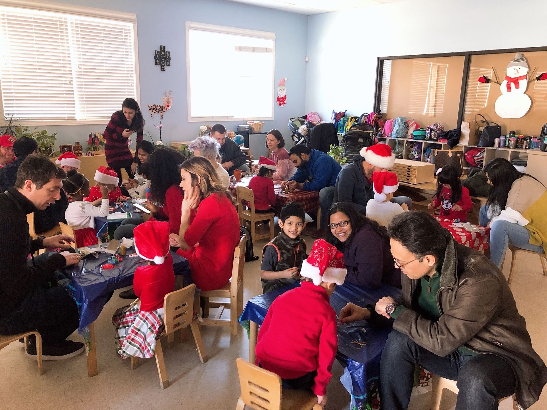 A group of people are sitting at tables in a room decorated for christmas.