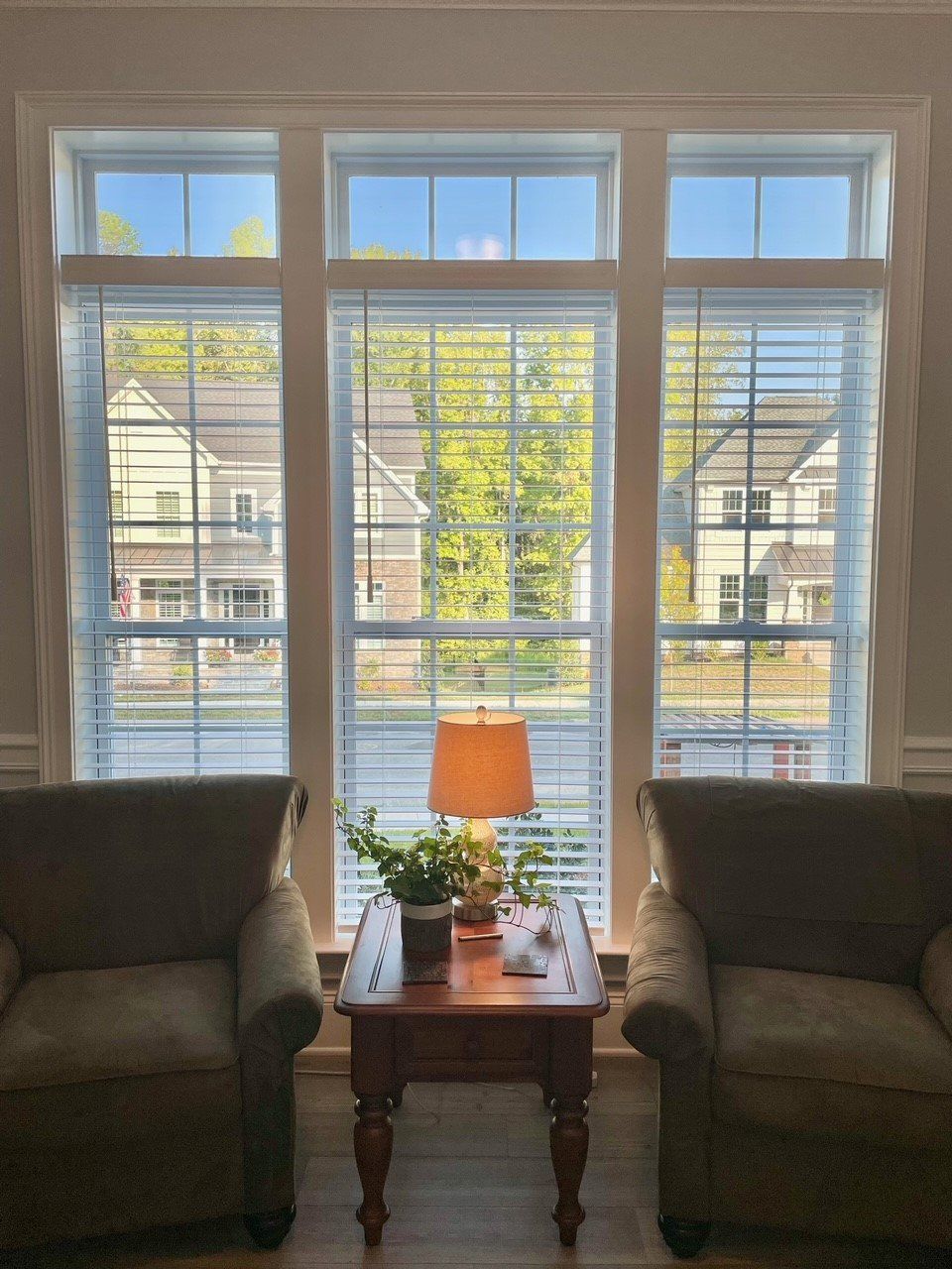 A living room with two chairs and a table with a lamp on it