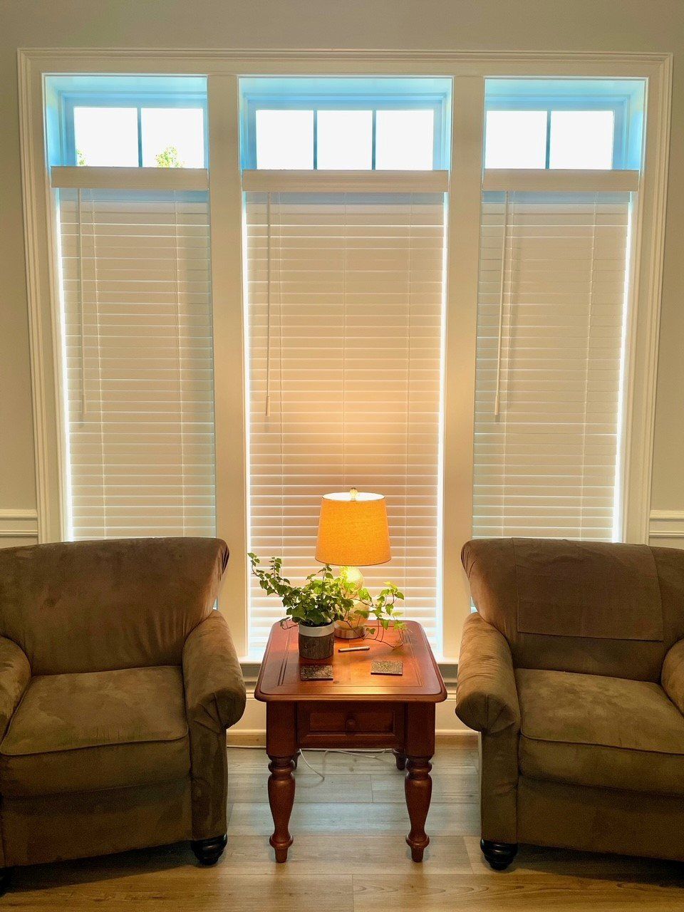 A living room with two chairs , a table , and a lamp.