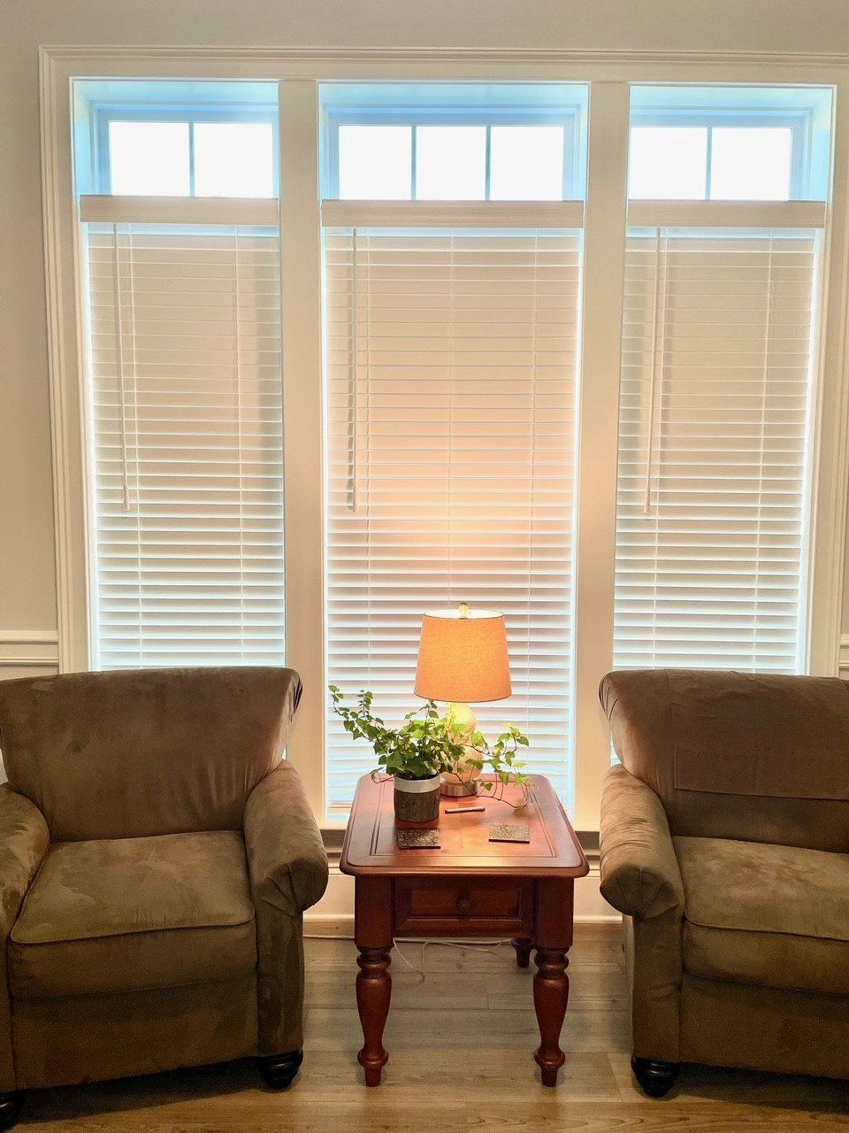 A living room with two chairs , a table and a lamp.