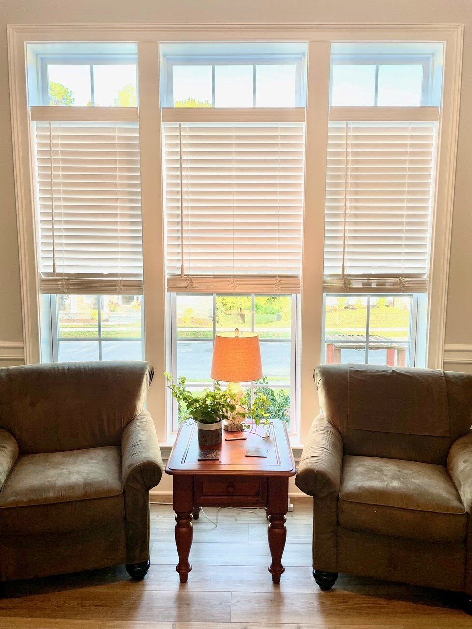 A living room with two chairs , a table , and a lamp.