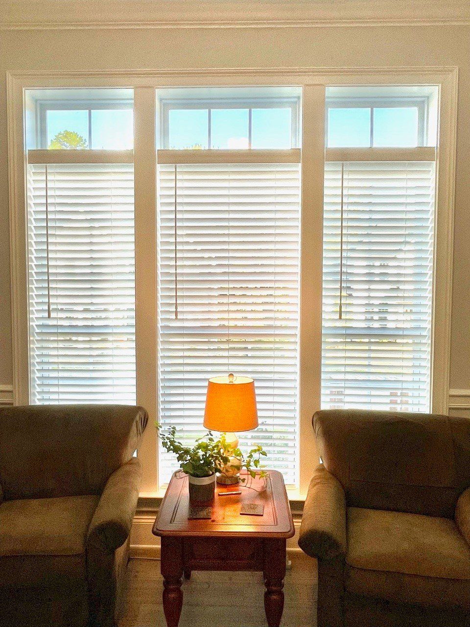 A living room with two chairs a table and a lamp
