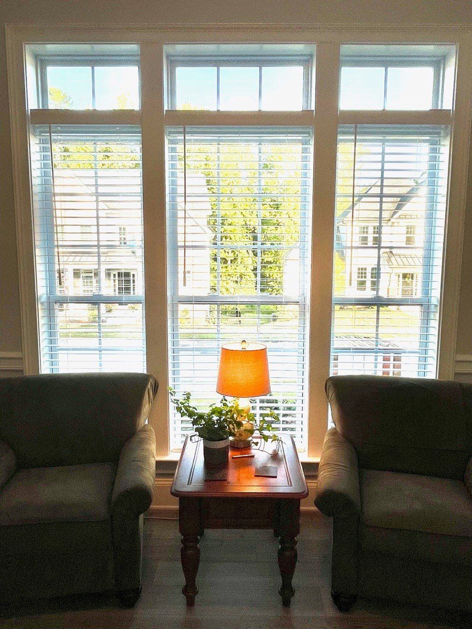 A living room with two chairs and a table with a lamp on it