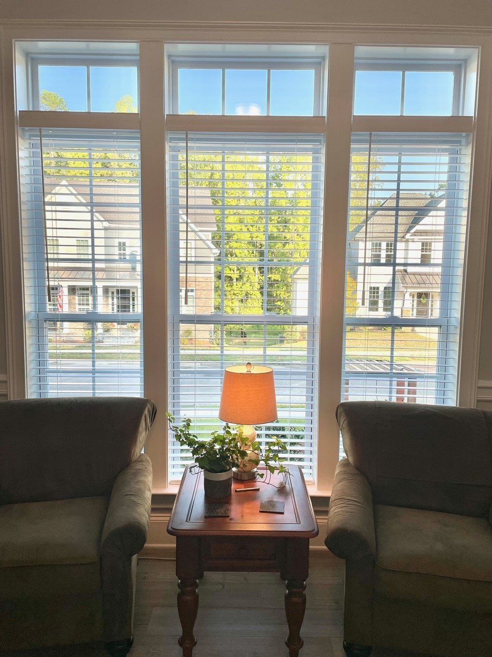 A living room with two chairs and a table with a lamp on it