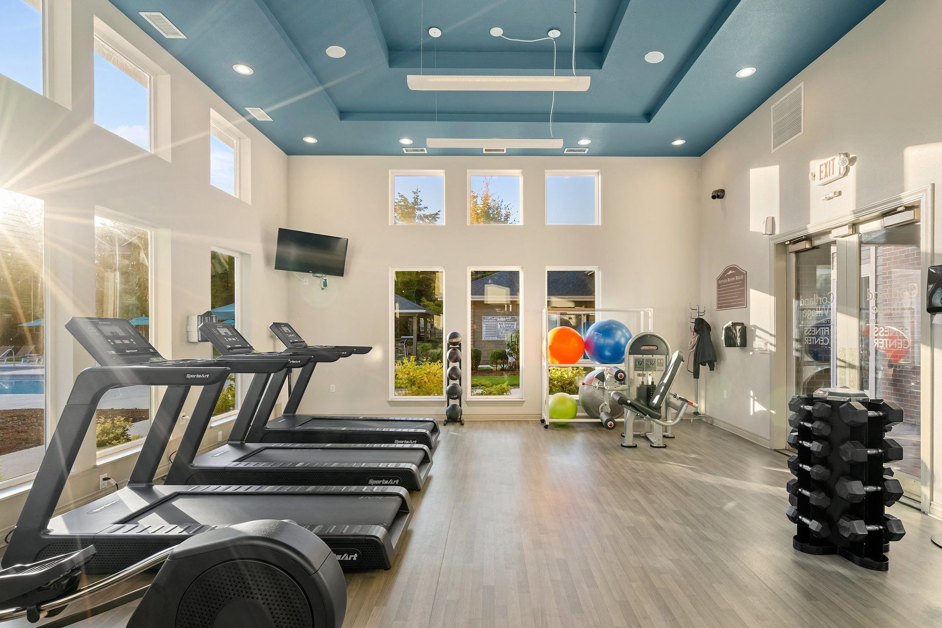 Well-lit indoor fitness center with treadmills, weights, and exercise equipment.
