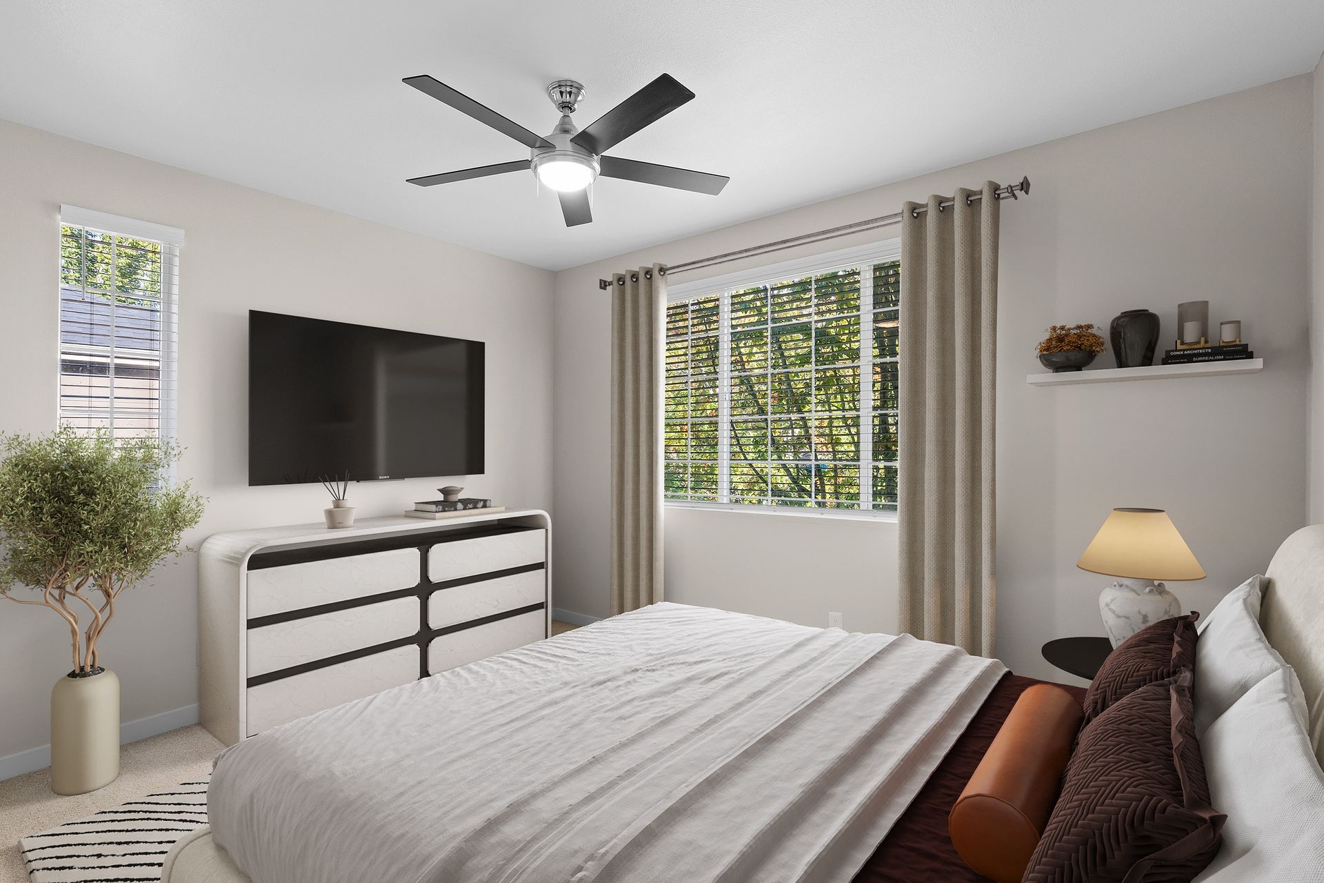 Bedroom with wall-mounted TV, dresser, bed, ceiling fan, and large window with blinds.