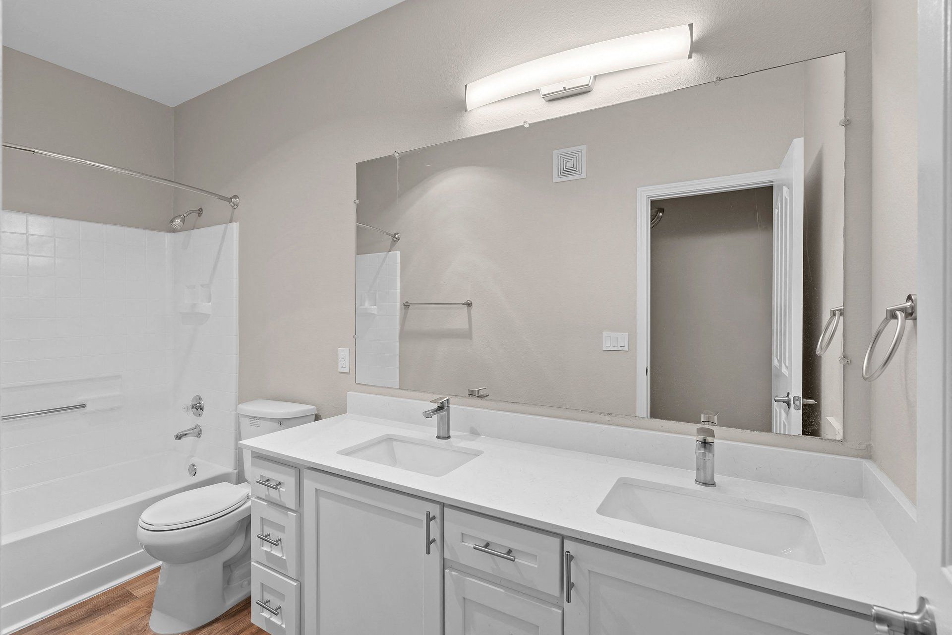 Bathroom with double vanity, large mirror, toilet, and a tub/shower combo.