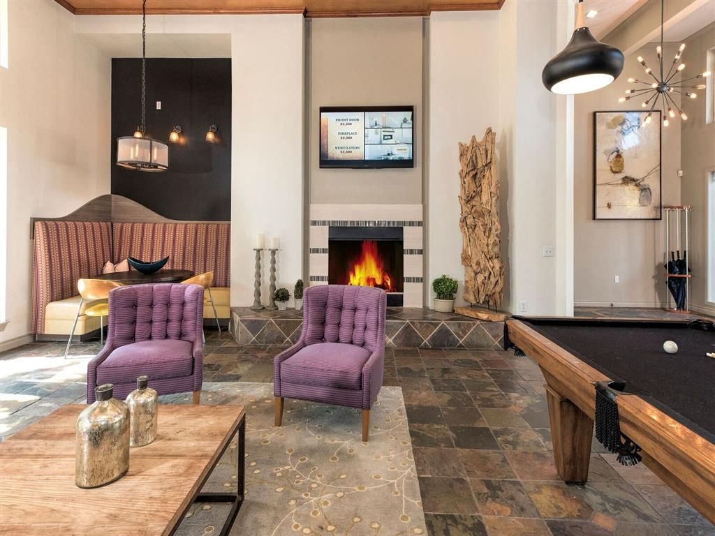 Communal lounge with fireplace, purple armchairs, and a pool table.