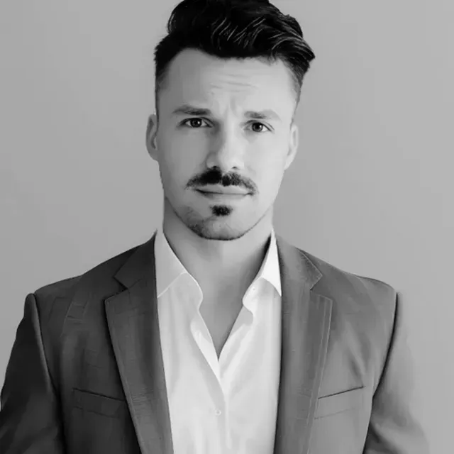 Man in a suit, looking directly at the camera, neutral expression. Black and white.