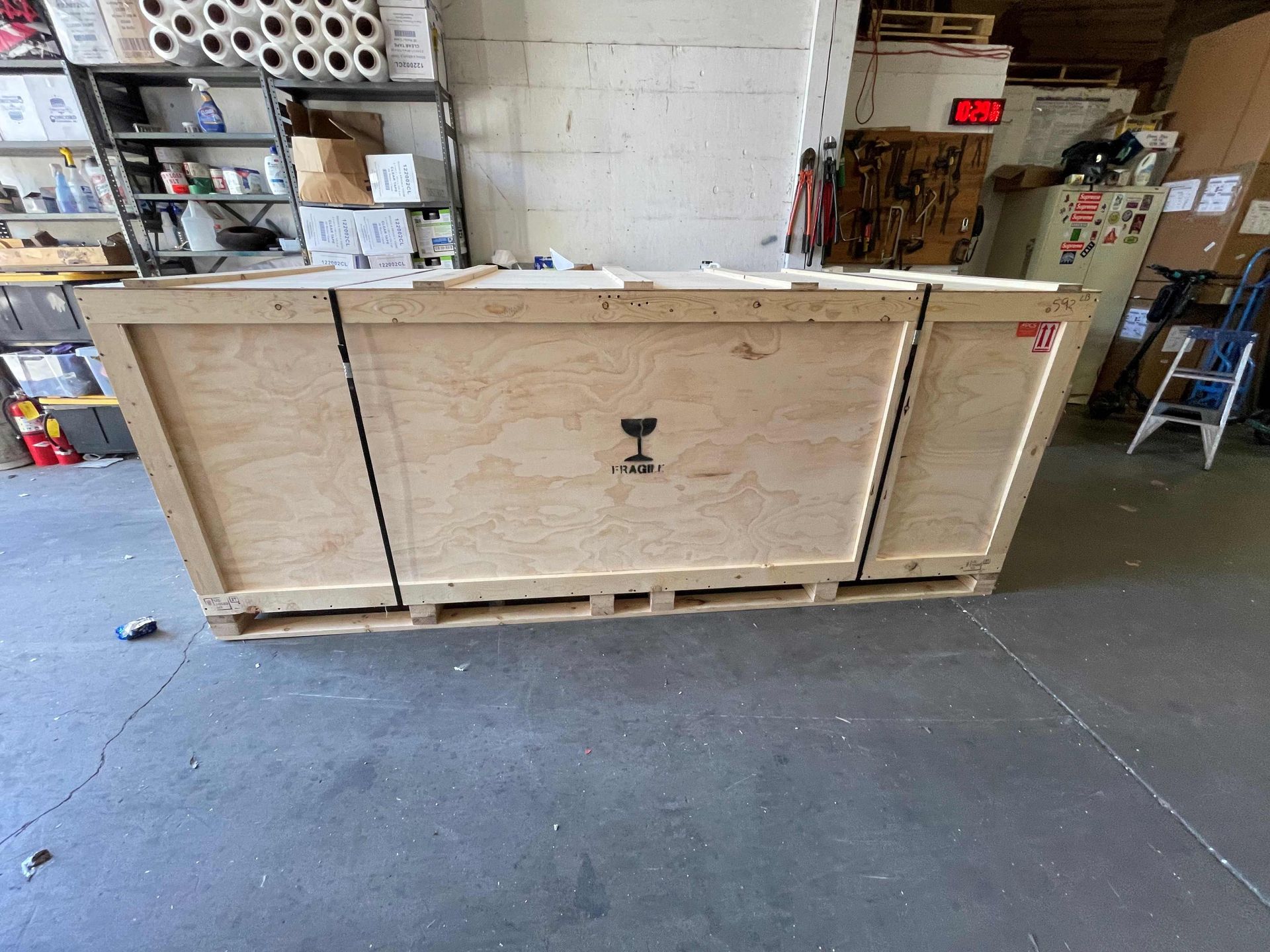 A large wooden box is sitting on the floor in a garage.