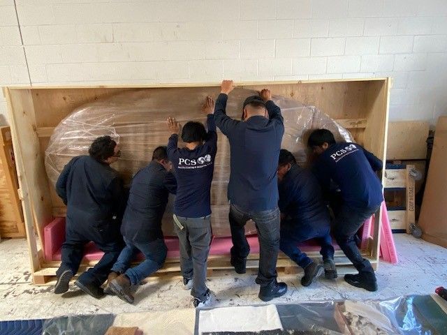 A group of men are pushing a large wooden box.