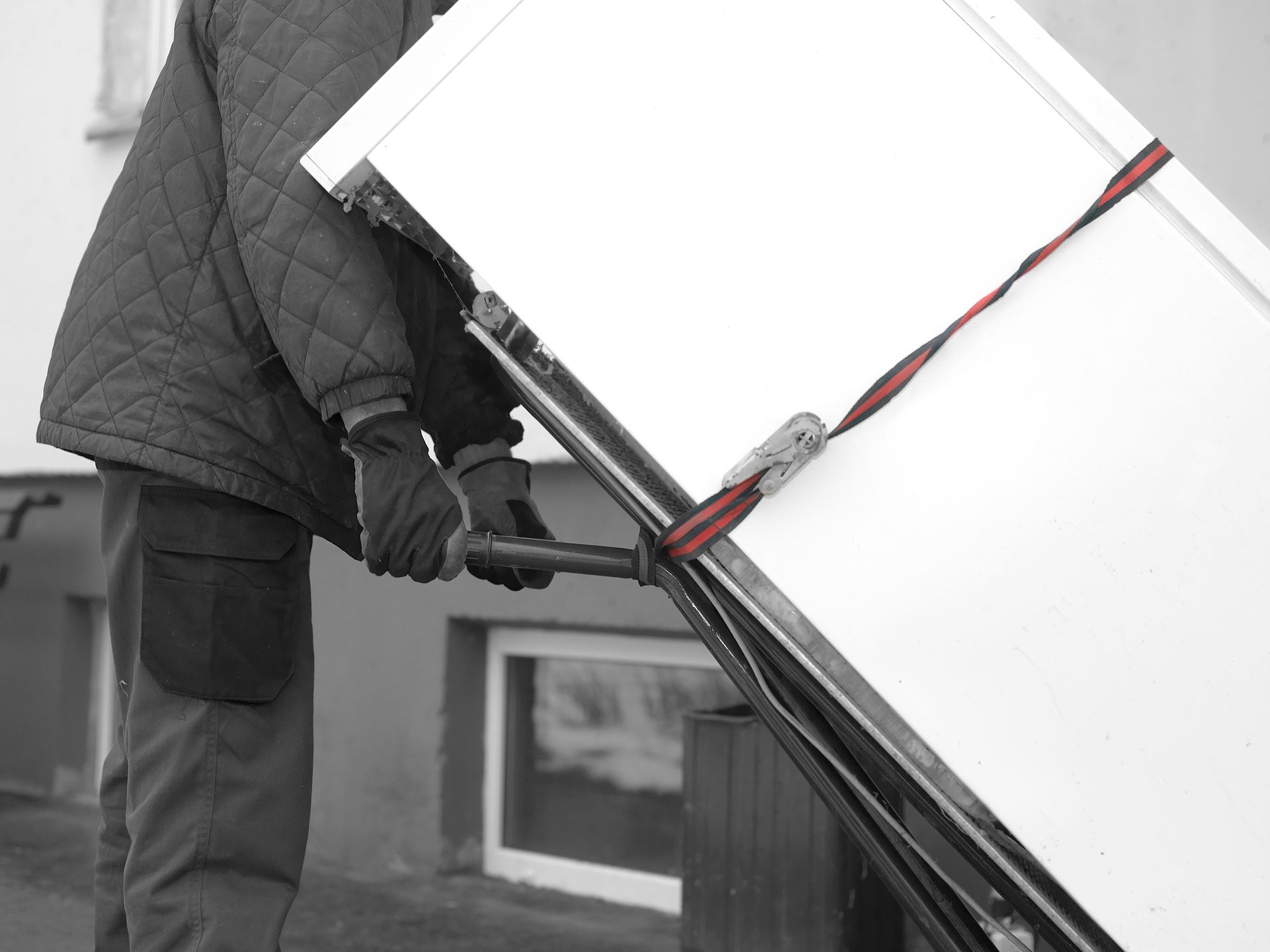 A man is carrying a large piece of paper on a cart. Safe, reliable appliance moving.