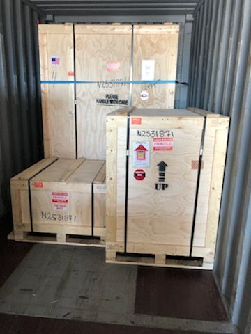 Two wooden crates are stacked on top of each other in a shipping container.