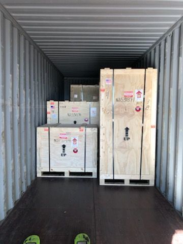 A shipping container filled with wooden crates and pallets.