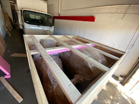 A white truck is parked in a garage next to a wooden box.