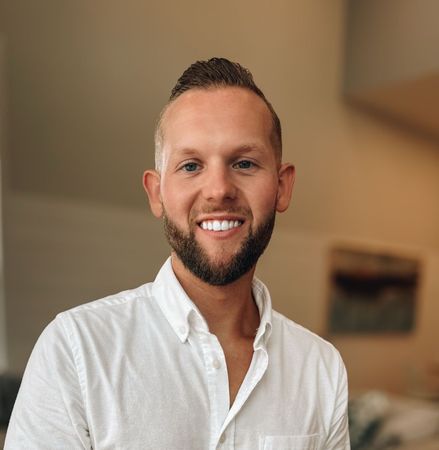 A man with a beard and tie is smiling for the camera.