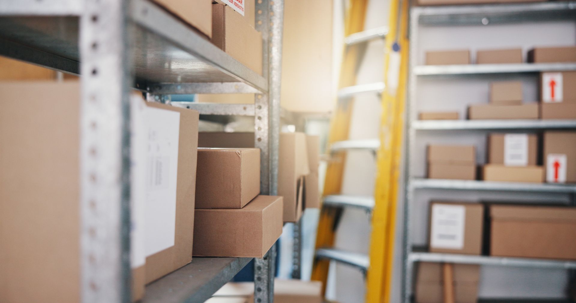 Shelves in a warehouse aisle holding cardboard boxes and packages