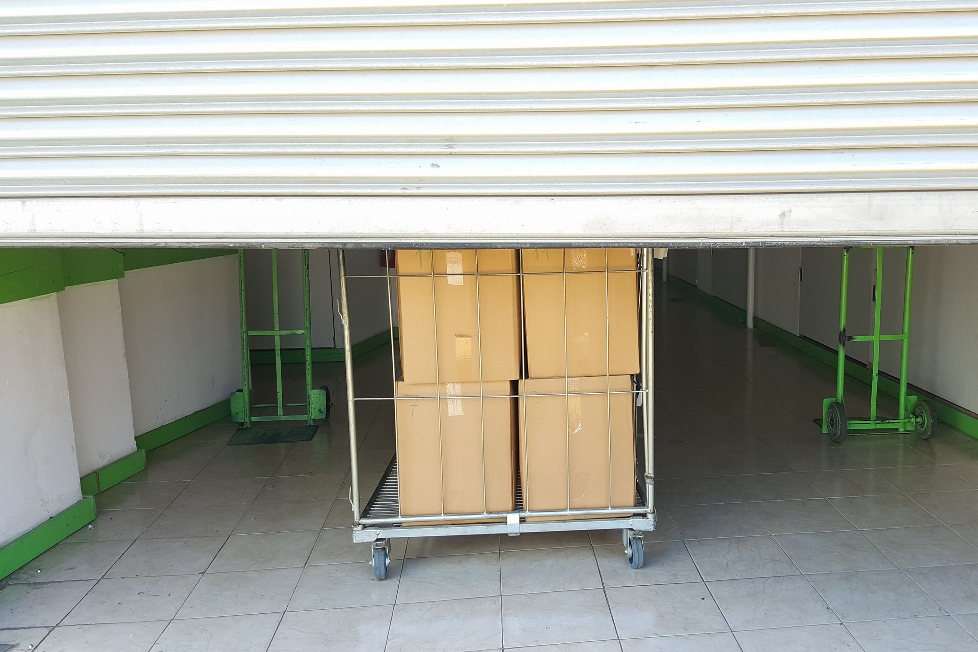 Large cart with boxes at the entrance to metal-door storage unit, ready for loading or unloading.