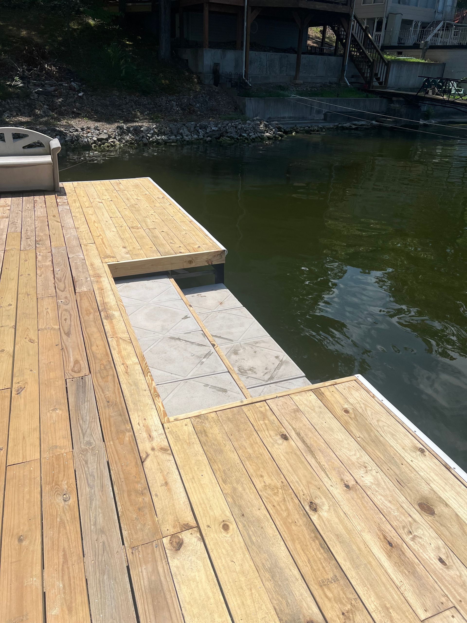 Wooden dock extending into dark water; ramp to a lower platform.