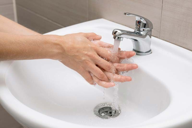 A person is washing their hands in a bathroom sink.