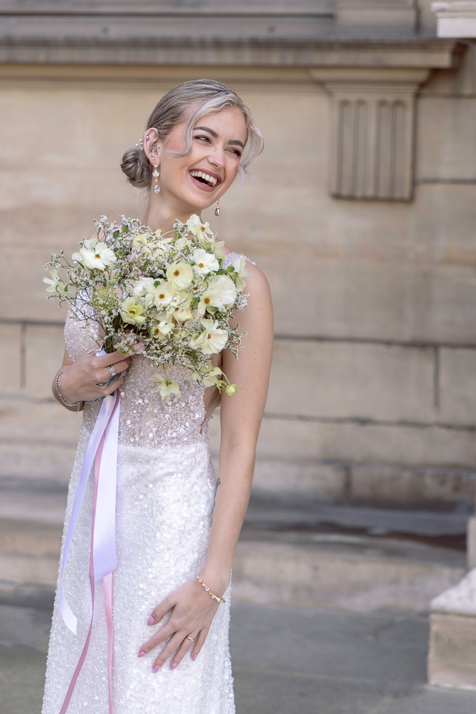 Een vrouw in een trouwjurk houdt een boeket bloemen vast en glimlacht.