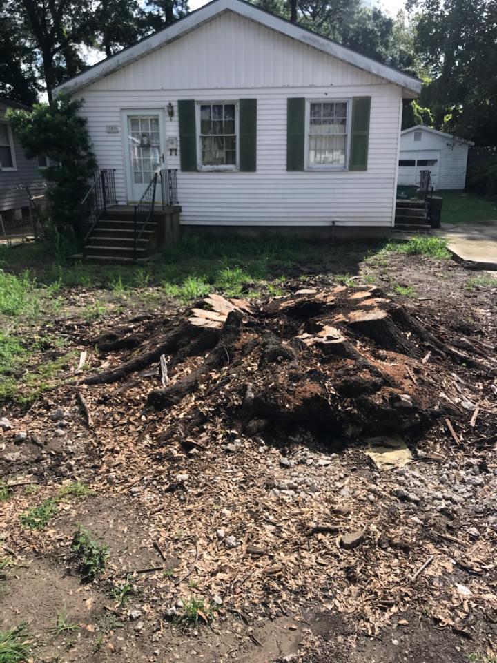 A white house with green shutters and a pile of dirt in front of it. Tree Stump Grinding Service Metairie LA