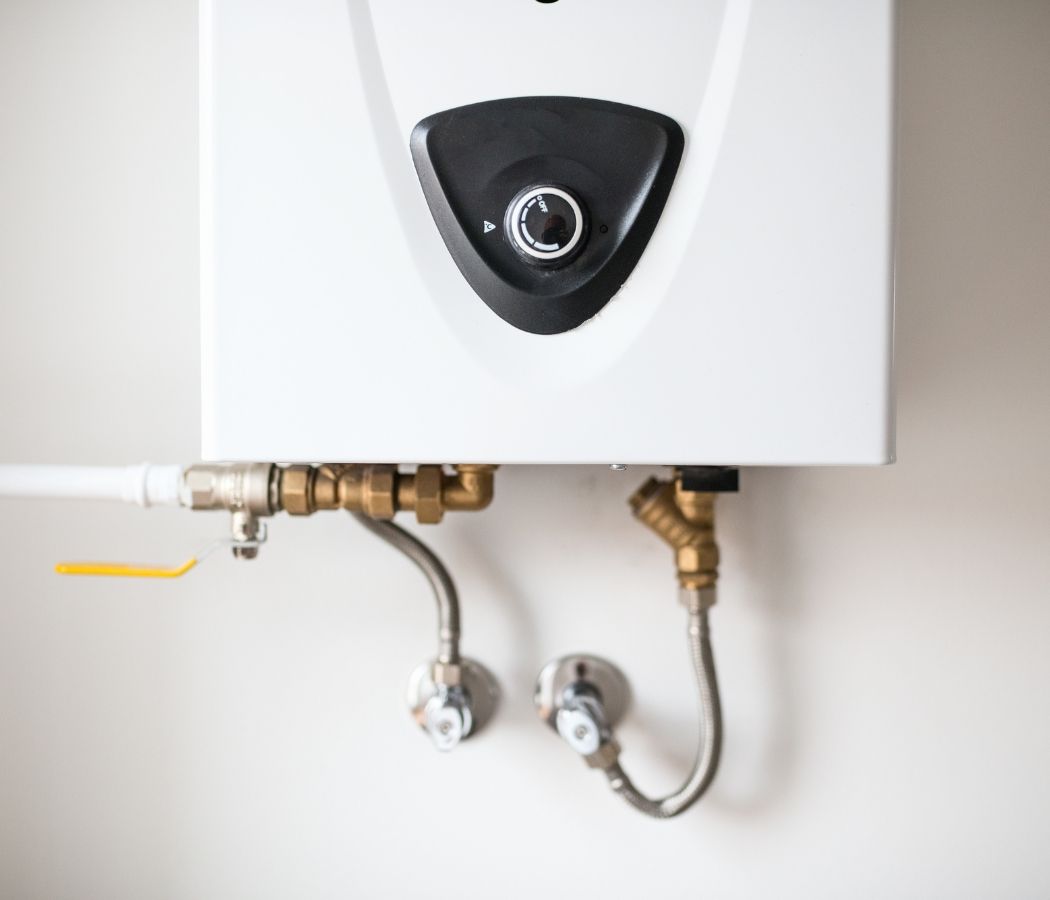 A white water heater with brass pipes attached to it