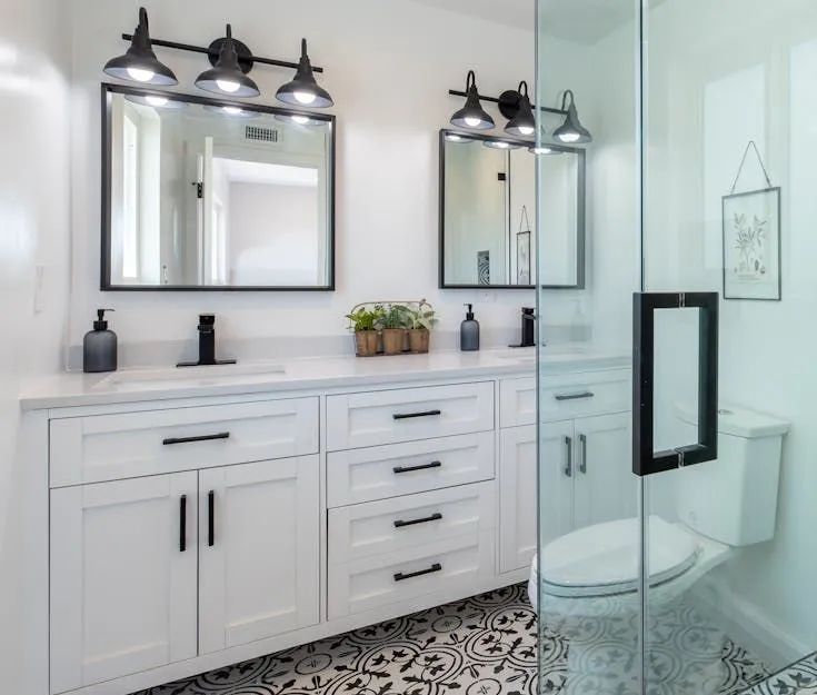 A bathroom with two sinks , a toilet , and a walk in shower.