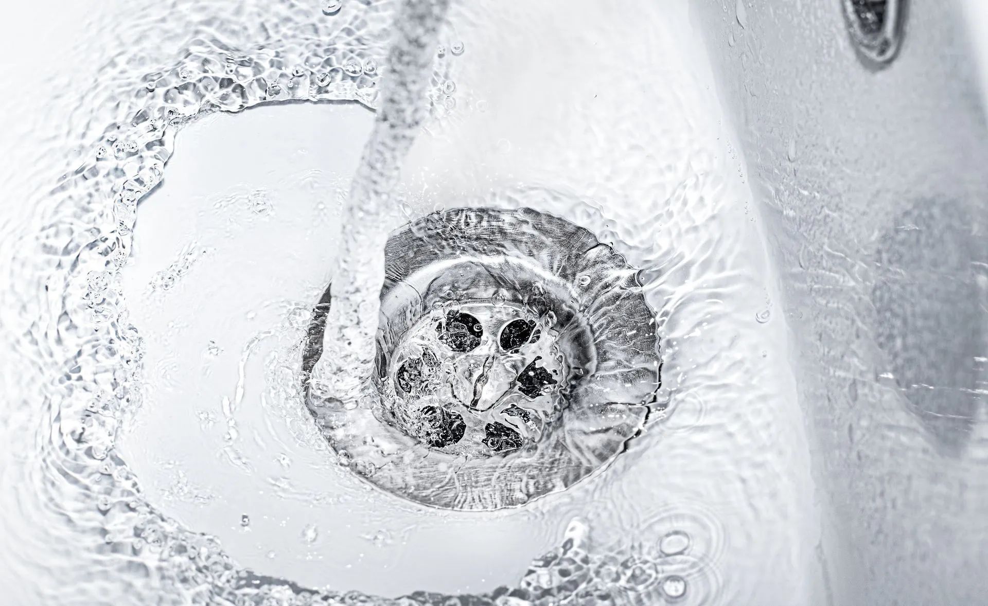 A close up of a sink with water running down the drain.